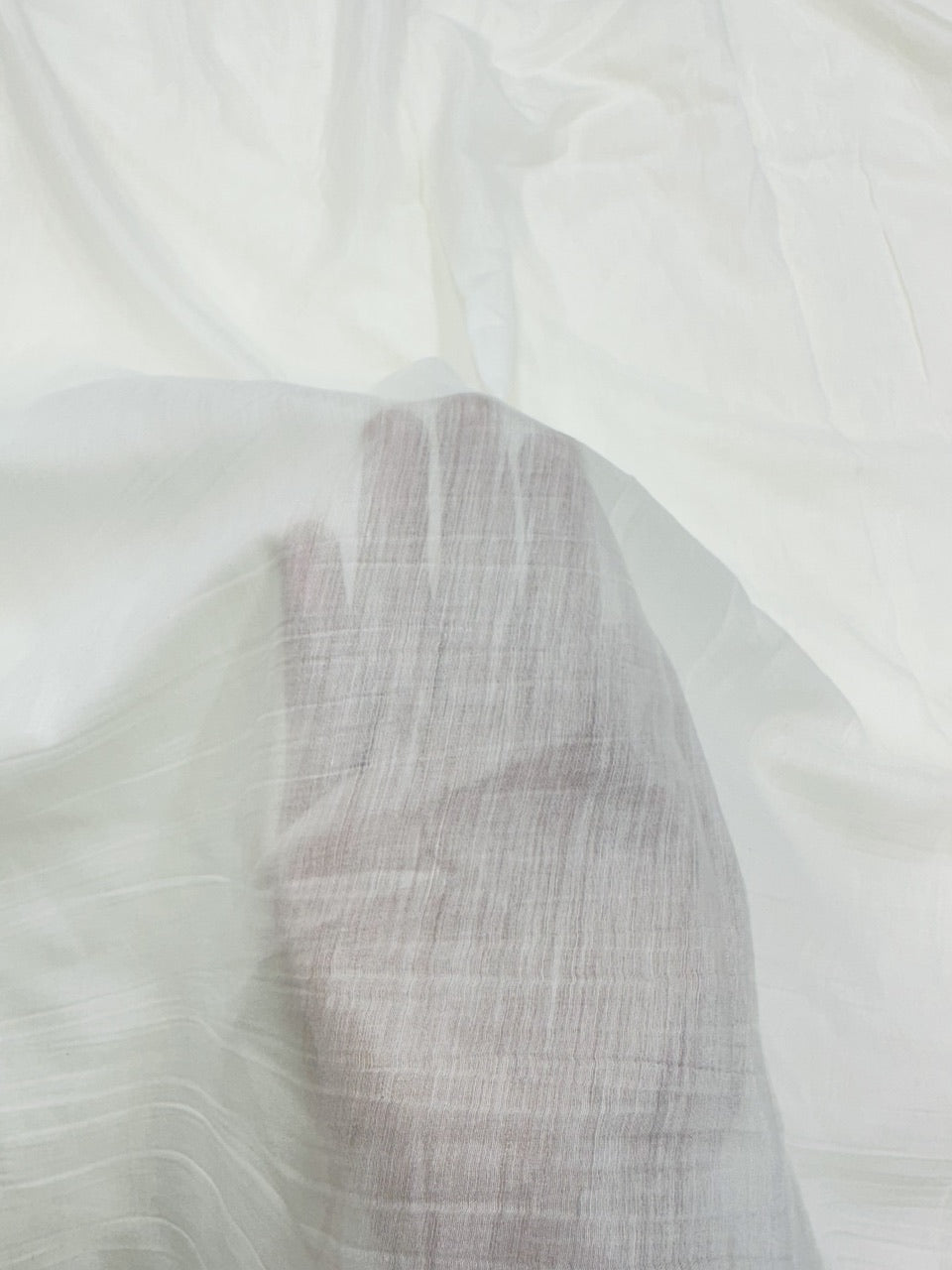 Close-up of a textured white mul mul chanderi fabric with a subtle pattern