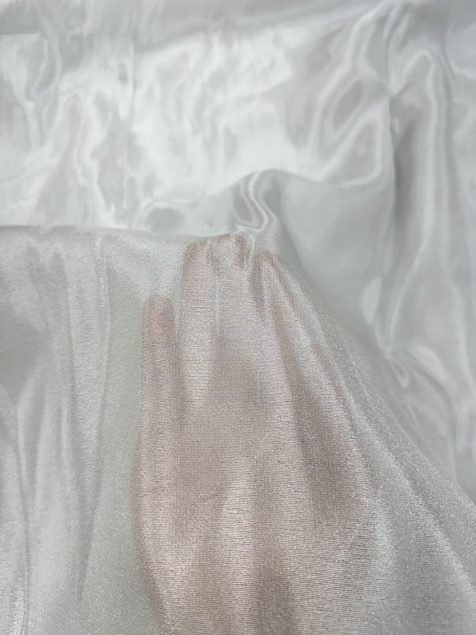 Close-up of textured silver shimmer tissue fabric with a hand holding it.