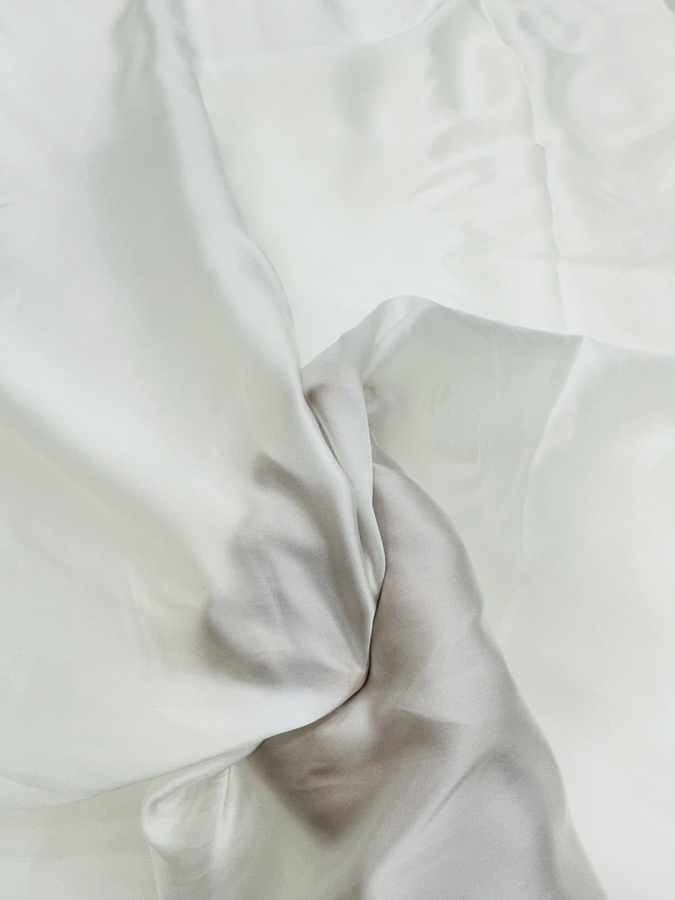 Close-up of white satin fabric with folds on a white background