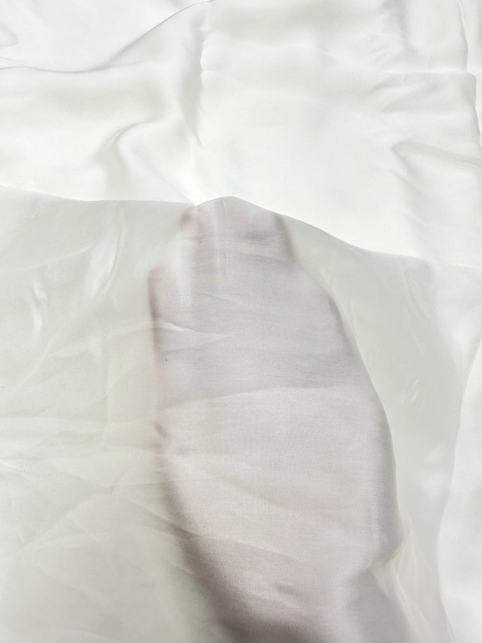 Close-up of white satin fabric with folds