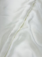 Close-up of pure white satin fabric with folds