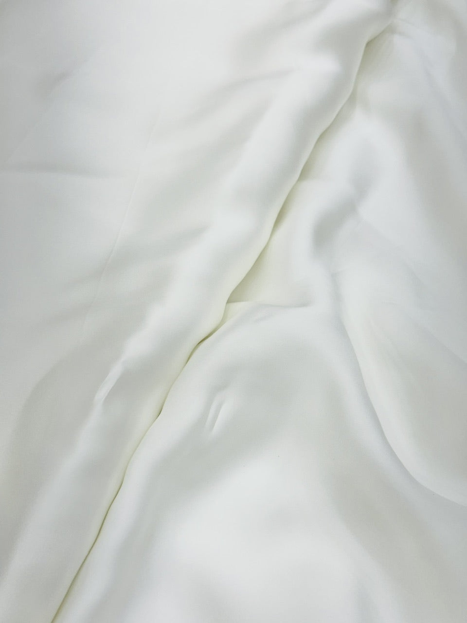 Close-up of pure white satin fabric with folds