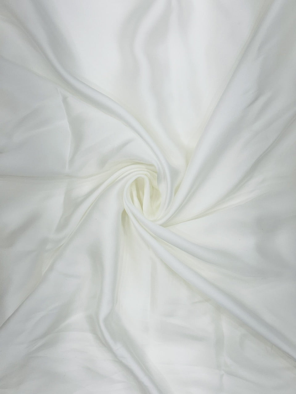 Close-up of pure white satin fabric with a swirl pattern