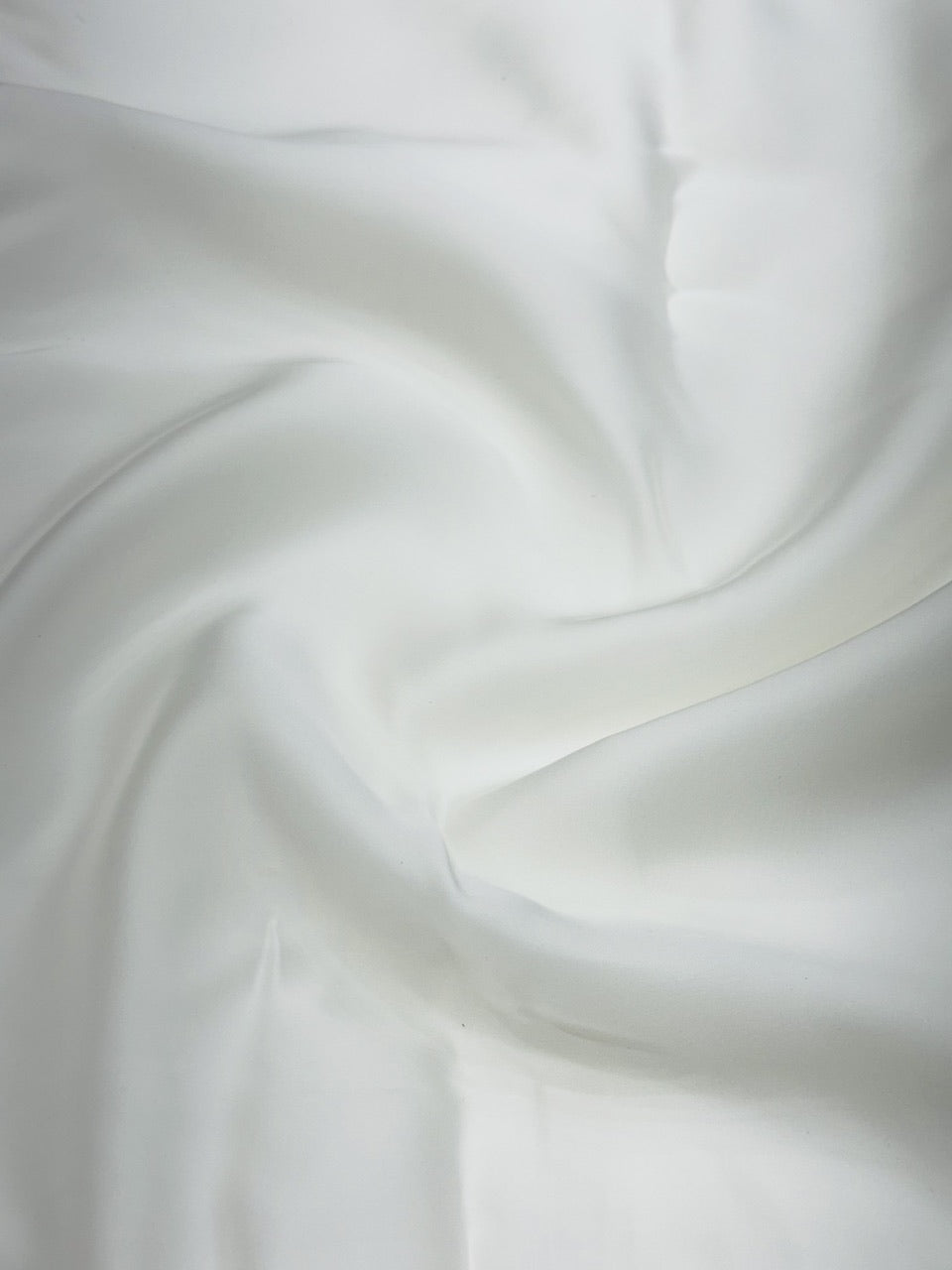 Close-up of pure white satin fabric with soft folds