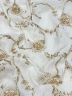 Close-up of white crepe fabric with intricate gold handwork beads embroidery