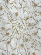 Close-up of white crepe fabric with gold floral handwork pattern