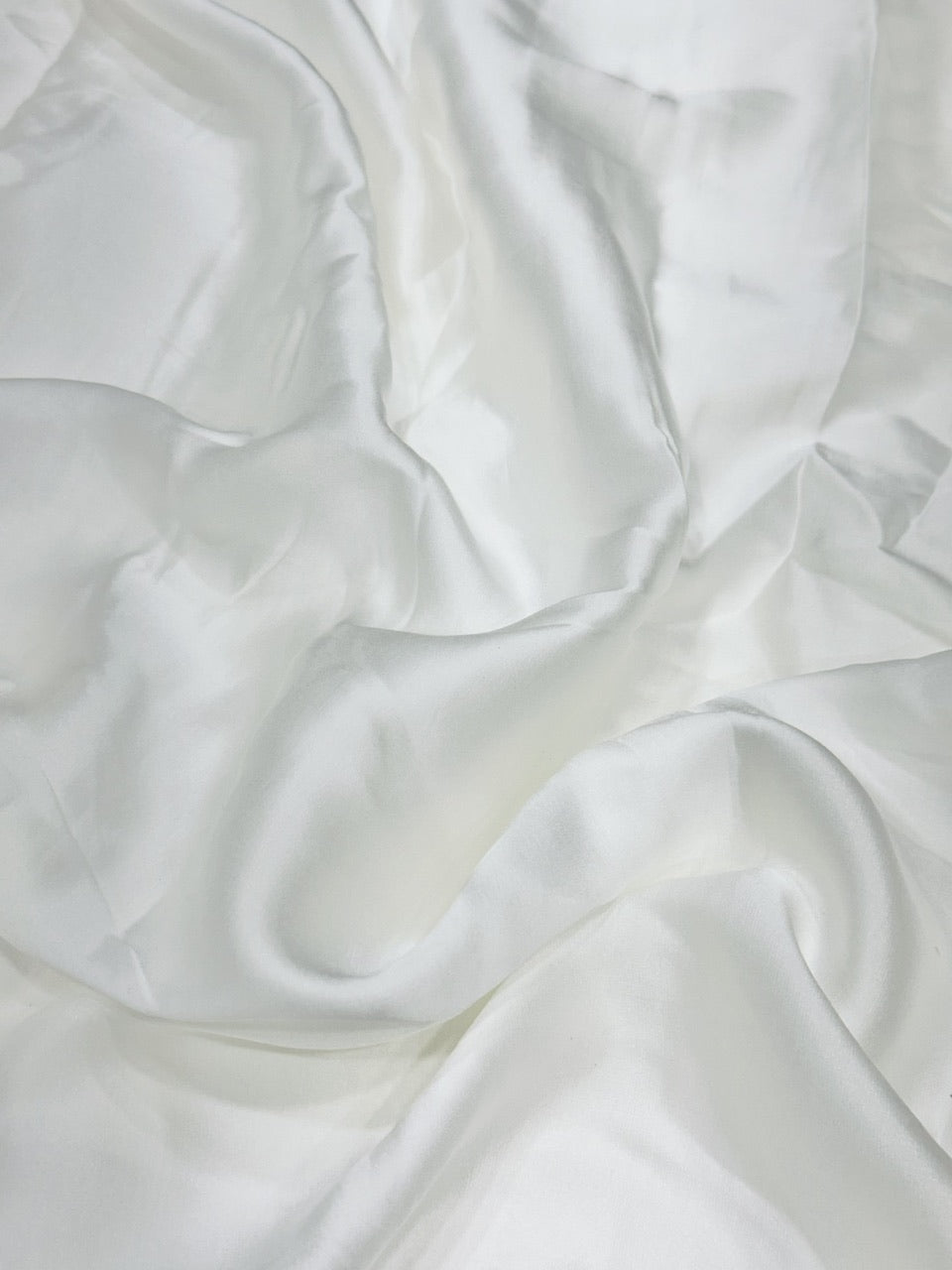 Close-up of white modal satin fabric with folds