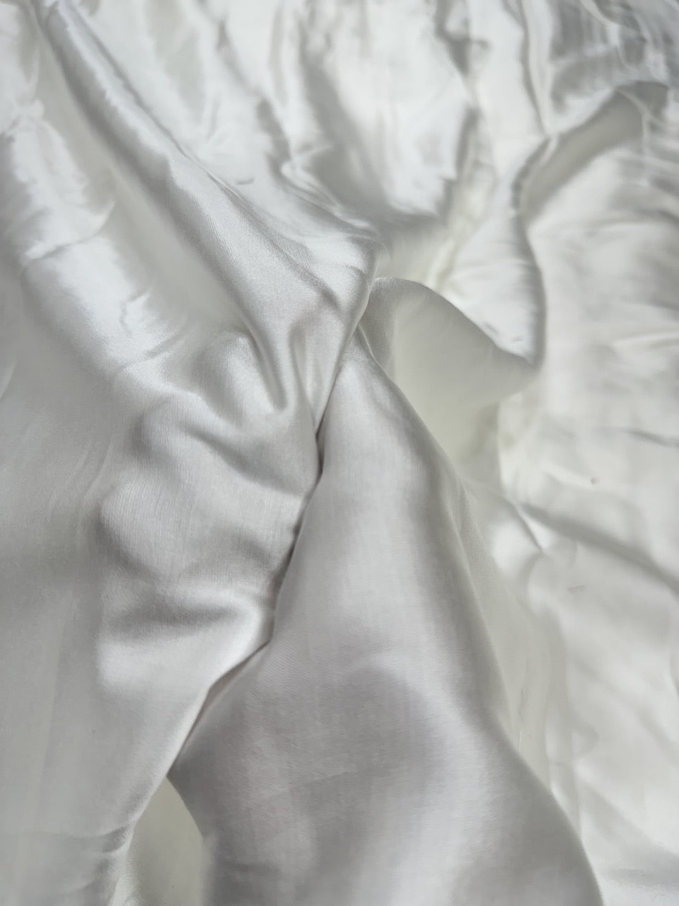 Close-up of white modal satin fabric with folds