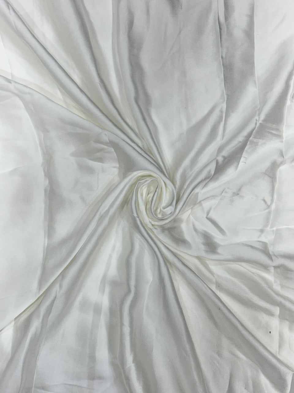 Close-up of white modal satin fabric with folds