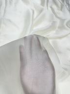 Close-up of white fabric with a hand on a white organza satin showing texture