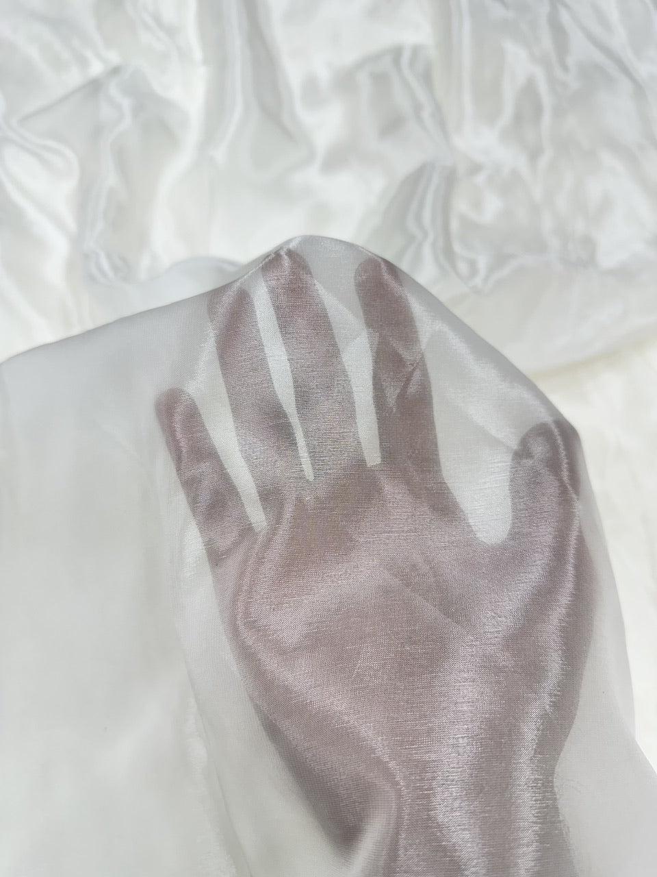 Close-up of a palm on a textured white glass organza fabric