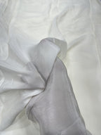 Close-up of white crepe fabric with folds with a hand holding the fabric
