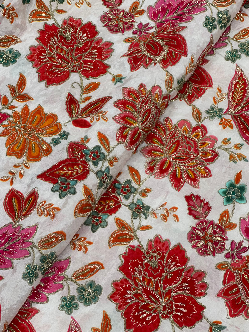 Close-up of a floral pattern with red, orange, and green colors on a white background.