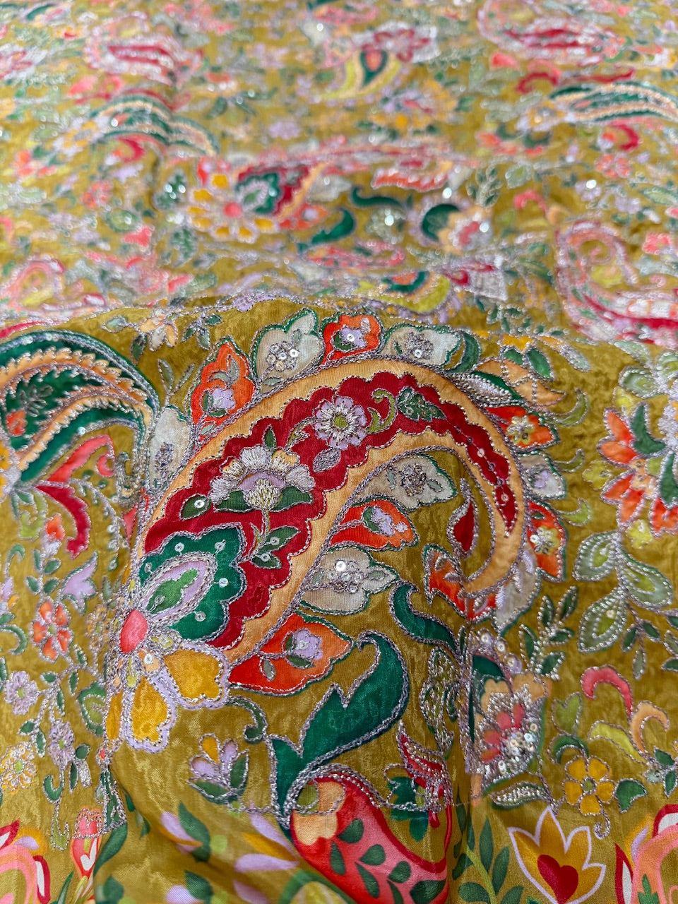 Close-up of a colorful embroidered fabric with intricate patterns and vibrant colors.