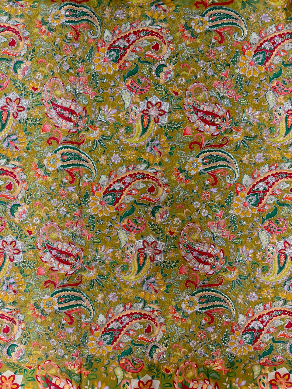Colorful paisley pattern fabric with intricate designs on a yellow background