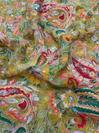 Close-up of a colorful paisley patterned fabric with red, green, and yellow colors.