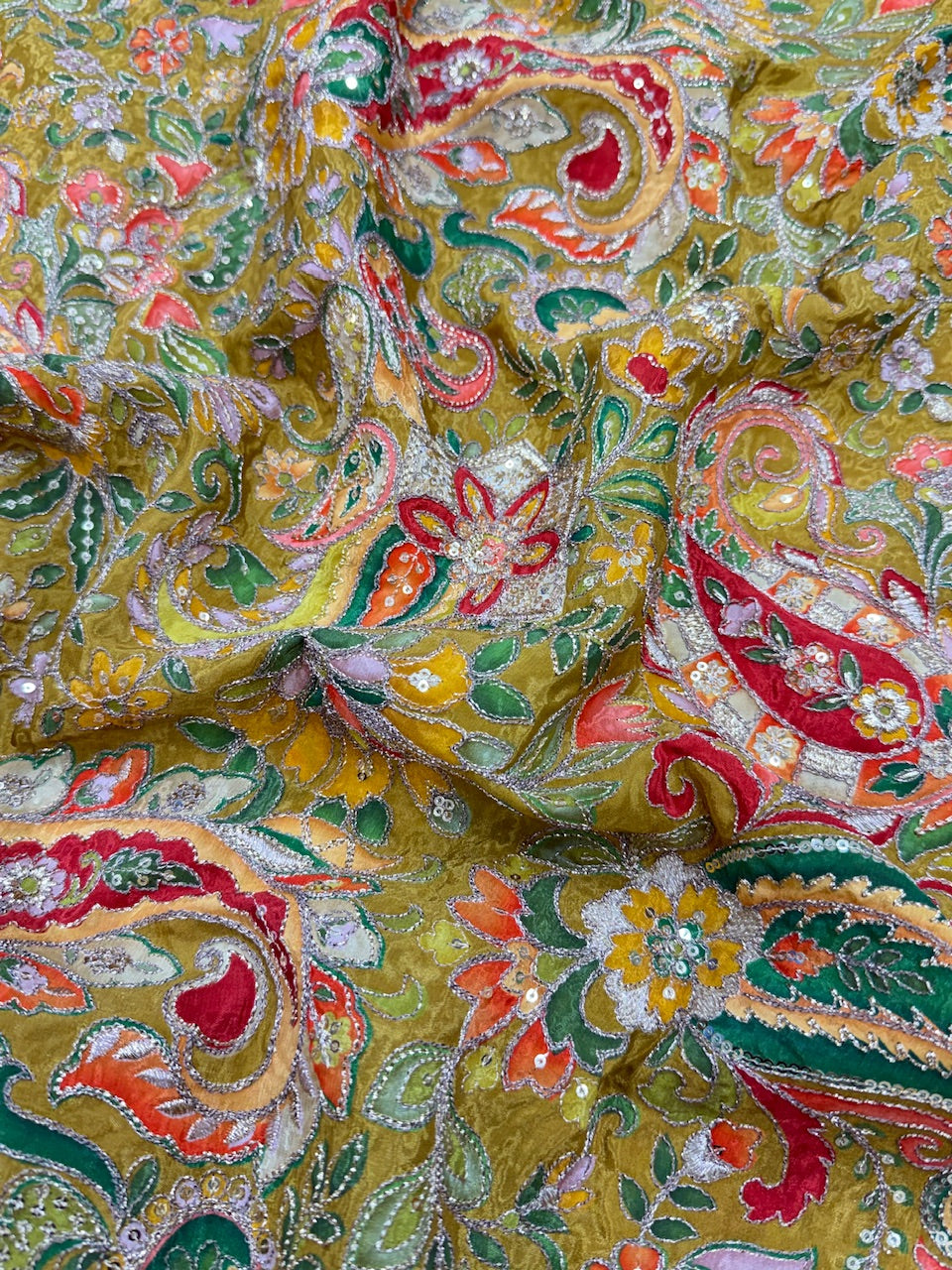 Close-up of a colorful paisley patterned fabric with red, green, and yellow colors.