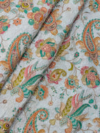Close-up of a fabric with intricate paisley and floral patterns in multicolors on a light background.