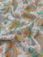 Close-up of embroidered fabric with colorful paisley patterns on a blue background