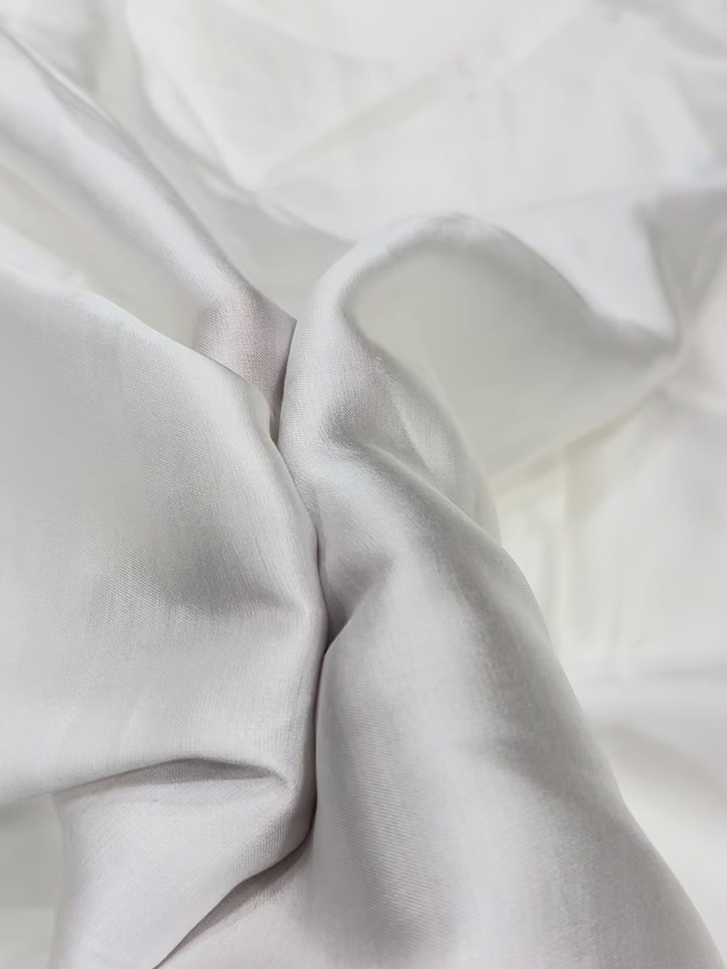 Close-up of white modal satin fabric with folds