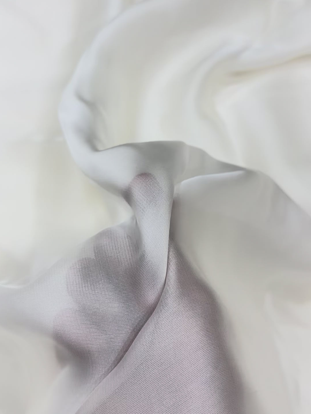 Close-up of white fabric with a hand on a white organza satin showing texture
